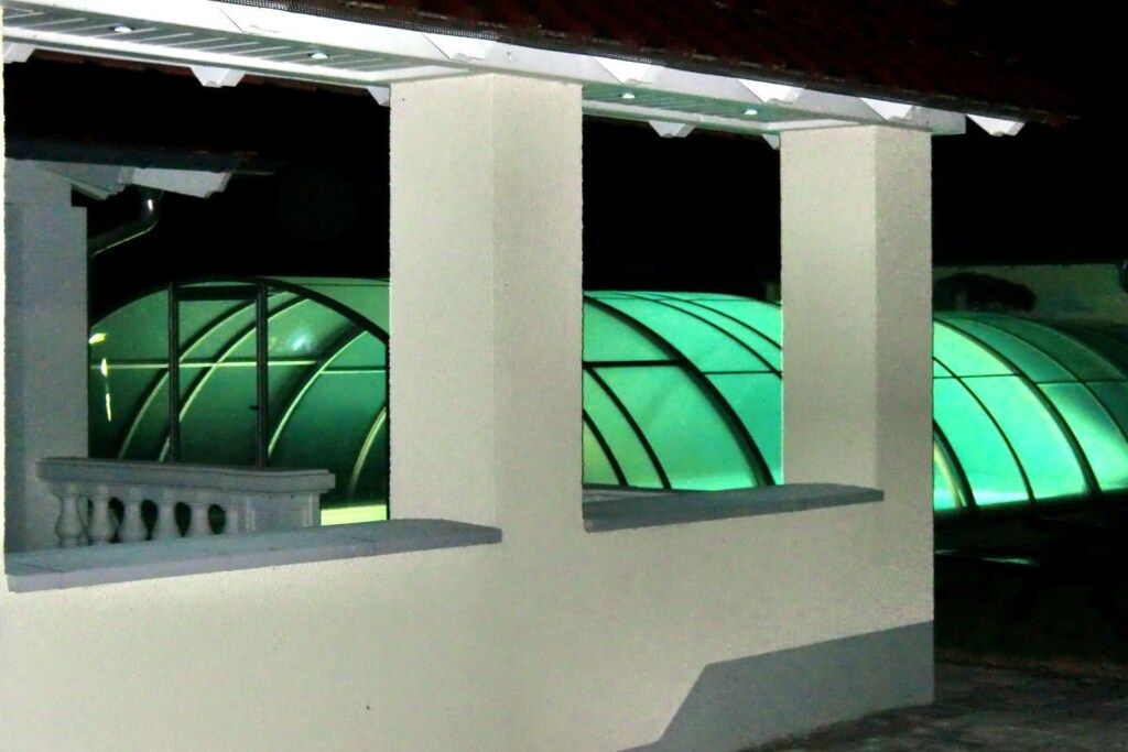 A building with a covered porch and a greenhouse structure.