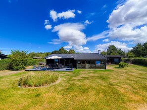 A modern house with a large glass patio, a swimming pool, and a well-maintained lawn.