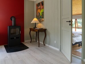 A room with a wood-burning stove, a table with a lamp, and a bed visible through an open door. - "Aapeli" - 3.9km from the sea by Interhome (Eskebjerg)