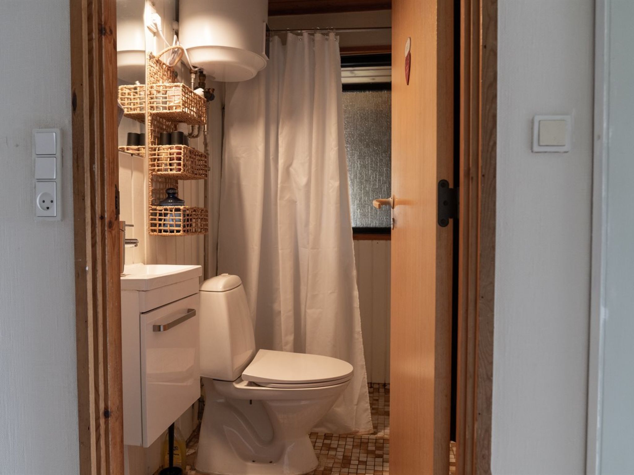 A compact bathroom with a toilet, a sink, and a shower curtain.
