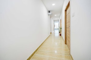 A long, narrow hallway with a wooden floor and white walls. - Townhouse Oak LB Nagar Metro Station (Hyderabad)