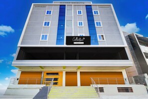 Un immeuble à étages doté d’une façade sobre, de grandes fenêtres et d’une enseigne indiquant qu’il s’agit d’un point de collecte géré par une entreprise.