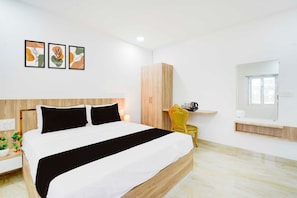 A modern bedroom with a bed, a wardrobe, a bedside table with a lamp, and a chair. - Townhouse Oak LB Nagar Metro Station (Hyderabad)
