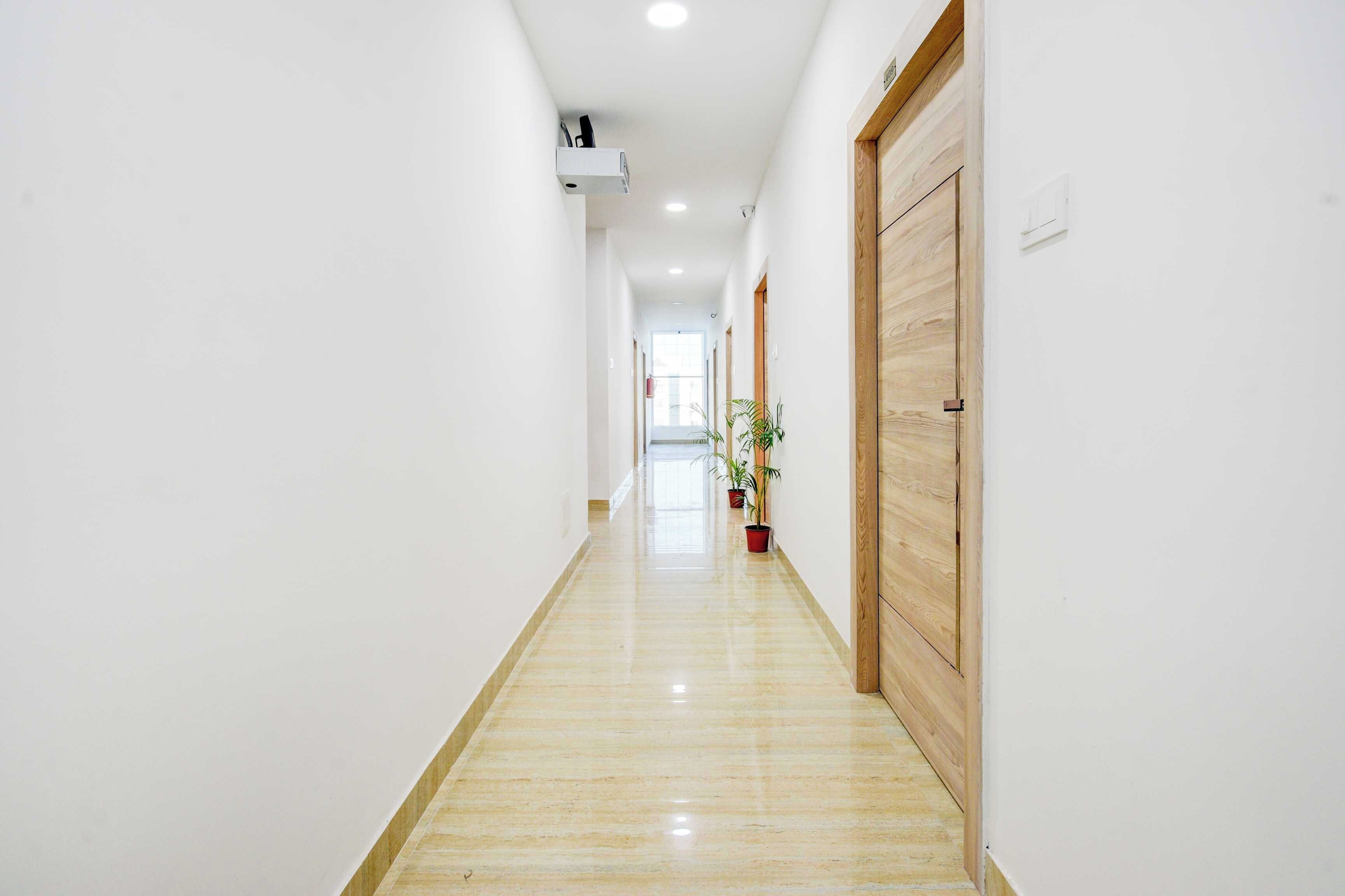 A long, narrow hallway with a polished floor, white walls, and wooden doors.