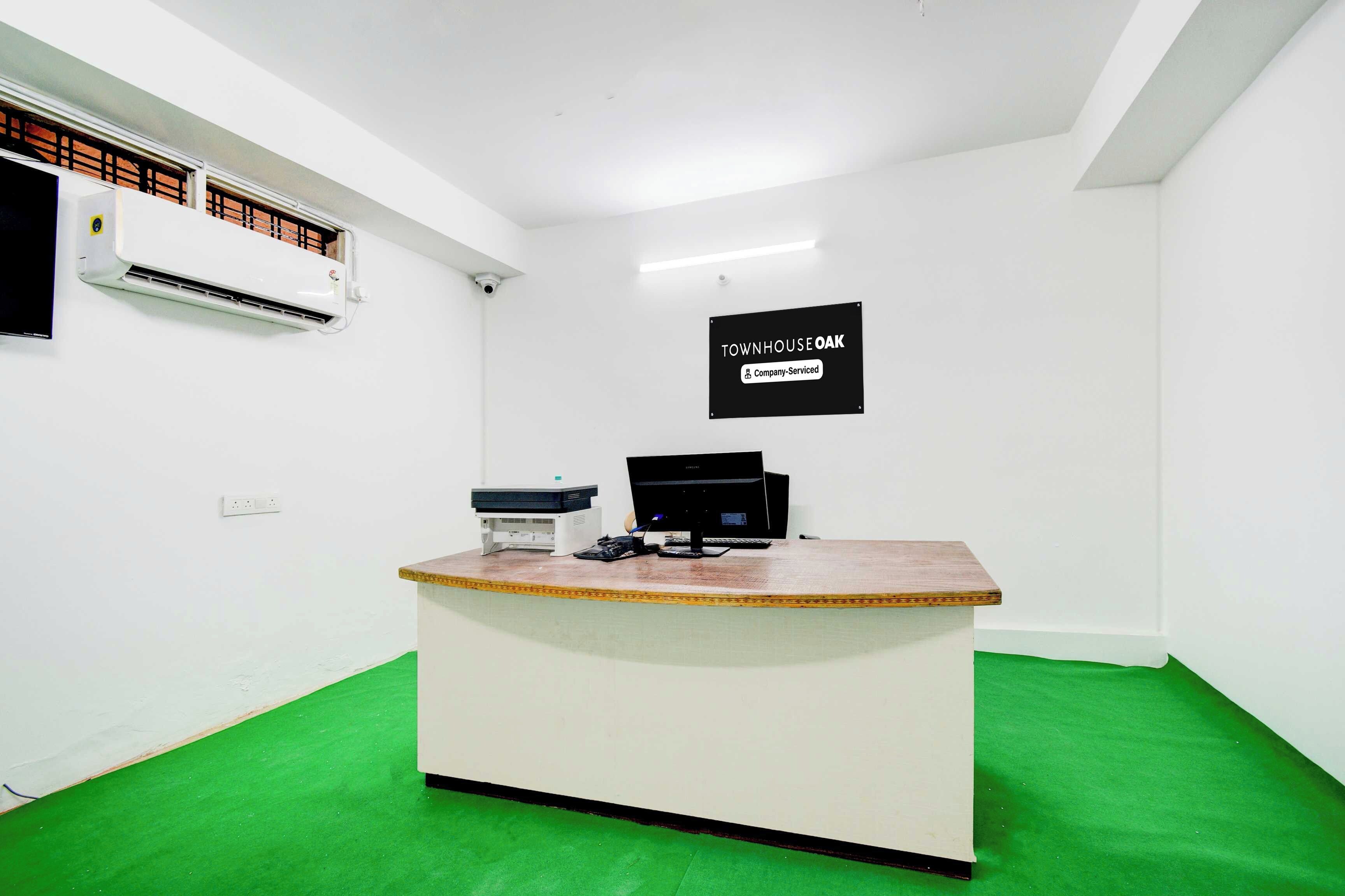 Mostrador de recepción con computadora, impresora y letrero que indica servicio de empresa.