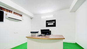 A reception desk with a computer, printer, and a sign indicating the property is company-serviced. - Townhouse Oak LB Nagar Metro Station (Hyderabad)