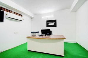 A reception desk with a computer, printer, and a sign indicating the property is company-serviced. - Townhouse Oak LB Nagar Metro Station (Hyderabad)