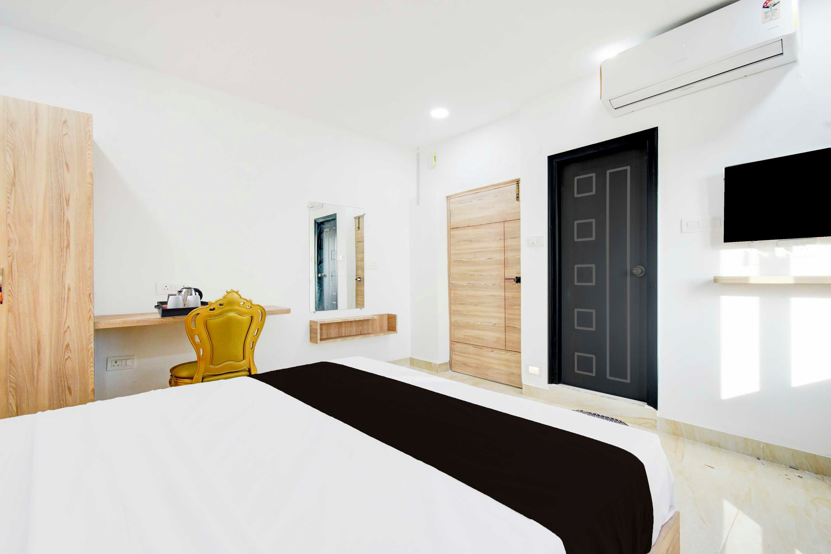 Una habitación de hotel con una cama, una silla, un armario, una puerta y un equipo de aire acondicionado.