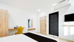 A hotel room with a bed, a chair, a wardrobe, a door, and an air conditioning unit. - Townhouse Oak LB Nagar Metro Station (Hyderabad)