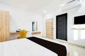 A hotel room with a bed, a chair, a wardrobe, a door, and an air conditioning unit. - Townhouse Oak LB Nagar Metro Station (Hyderabad)