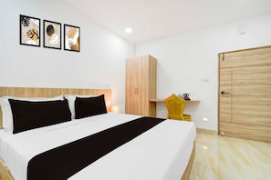 A hotel room with a bed, a wooden wardrobe, a yellow chair, and artwork on the wall. - Townhouse Oak LB Nagar Metro Station (Hyderabad)