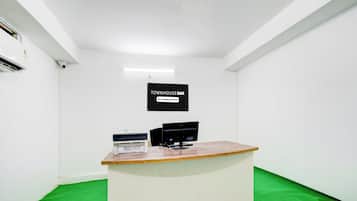 A clean, minimalistic room with a reception desk, a sign indicating it's a company-serviced location, and a green carpet.
