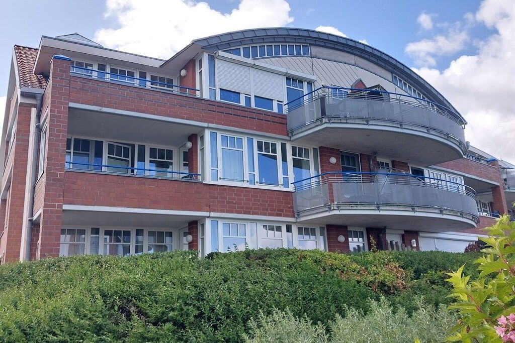 Un edificio residencial de varios pisos con balcones, techo curvo y fachada de ladrillo.