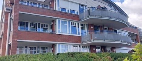 Ein mehrgeschossiges Wohngebäude mit Balkonen, einem gewölbten Dach und einer Ziegel-Fassade.