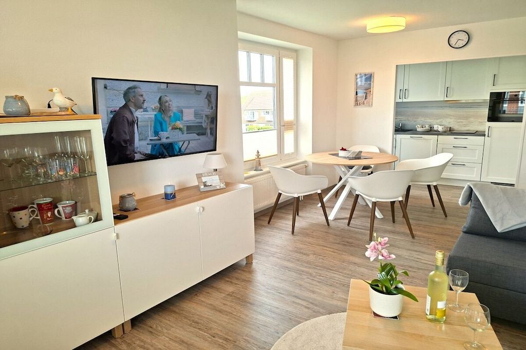 Una sala moderna con televisor, comedor y cocina.