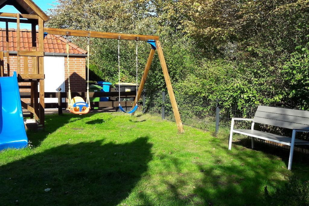A playground with a swing set, slide, and climbing structure.