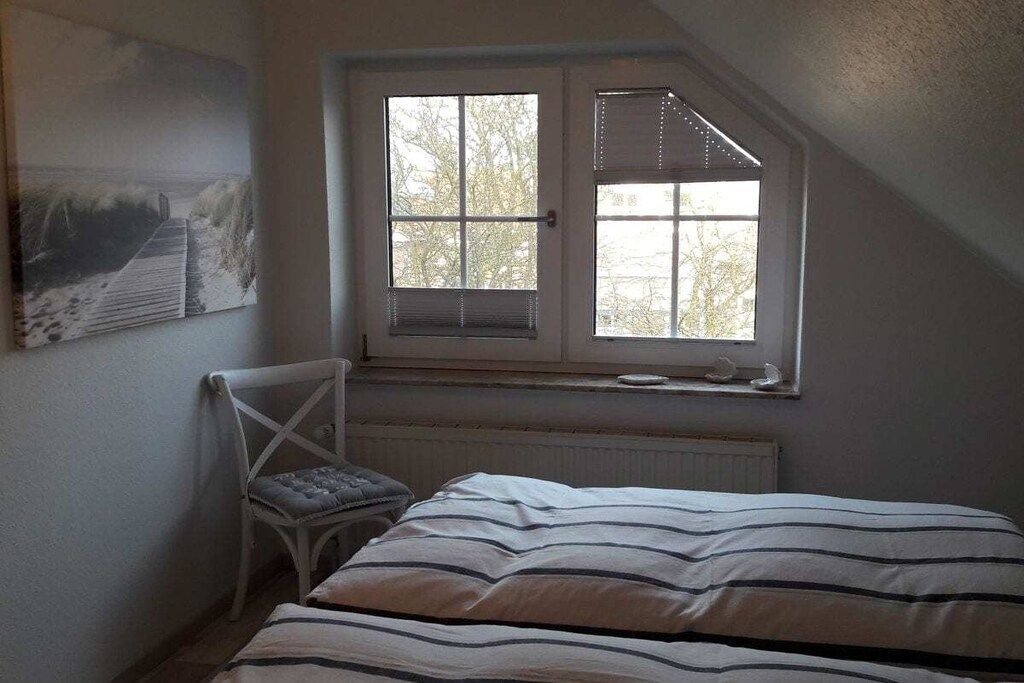 Une chambre à coucher avec un lit, une chaise, une fenêtre et un radiateur.