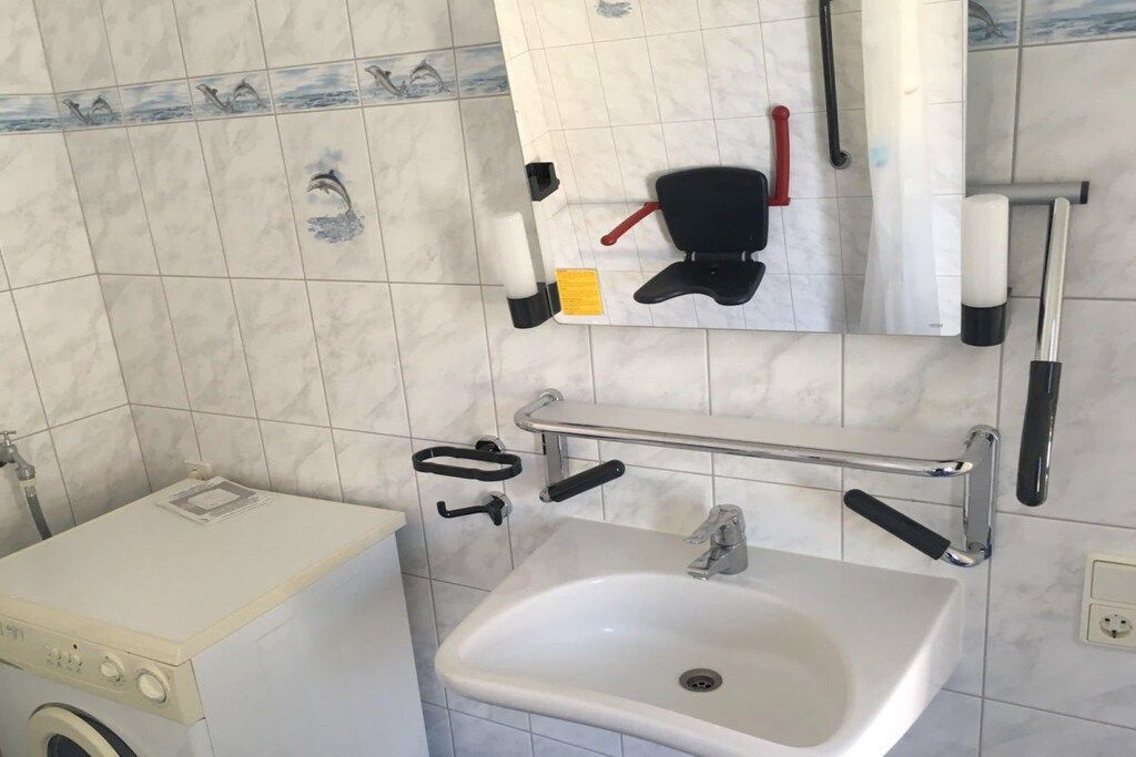 A bathroom with a sink, mirror, towel rack, and a washing machine.