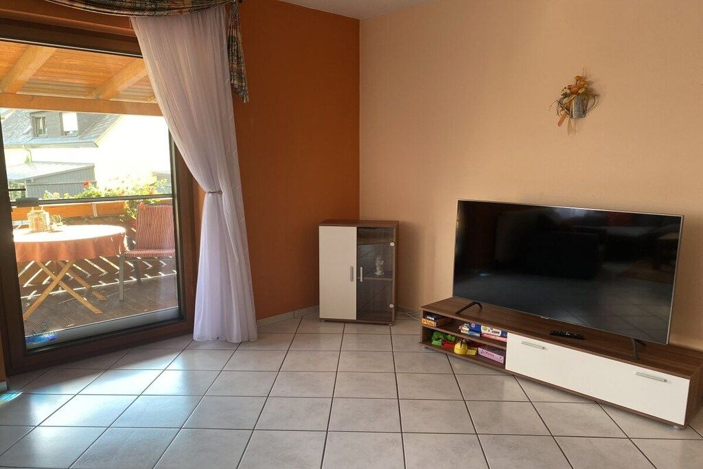 A living room with a large flat-screen TV, a cabinet, and a sliding glass door leading to an outdoor area.
