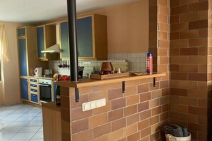 A kitchen with a brick backsplash, wooden cabinets, and a countertop with a kettle and a coffee maker. - Holiday apartment with 2 bedrooms (Graach)
