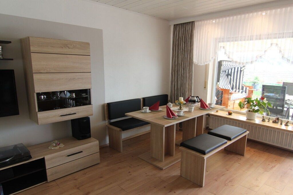 Une cuisine moderne avec un coin repas, des placards en bois intégrés et une fenêtre avec des rideaux.