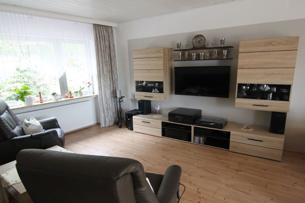 A modern living room with a flat-screen TV, wooden cabinets, and a comfortable seating area.