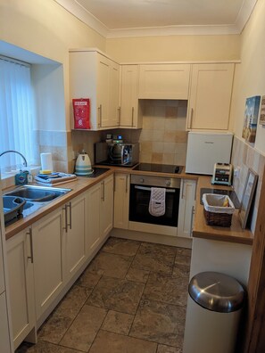 A compact kitchen with a built-in oven, a coffee maker, and a toaster. - Centrally located cosy pet friendly cottage. (Amble)