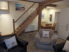 A living room with a staircase, a dining area, and a kitchen. - Centrally located cosy pet friendly cottage. (Amble)
