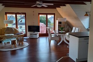 Una sala moderna con sofá, televisión, mesa de comedor y sillas.