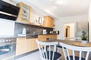 A modern kitchen with built-in appliances, wooden cabinets, and a dining area with white chairs. - Holiday apartment with 2 bedrooms (Bischoffen)