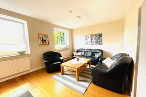 A living room with a sofa, armchairs, a coffee table, and artwork on the walls. - Holiday home in Fehmarn with swimming pool (Fehmarn)