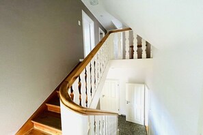 A staircase with wooden steps and white balusters leading to a landing with a door. - Holiday home in Fehmarn with swimming pool (Fehmarn)