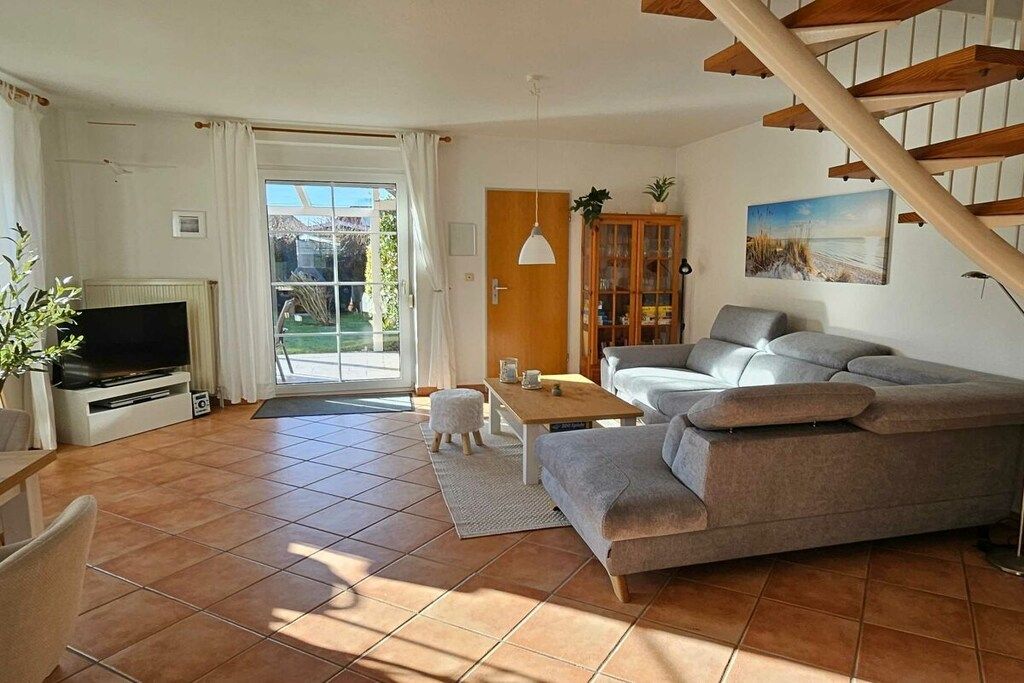 A living room with a sofa, a coffee table, a TV, and a staircase.