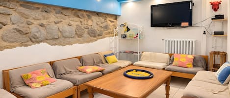 A living room with a stone wall, a television, and a wooden coffee table.