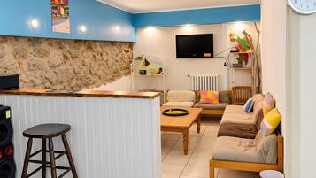 A modern living space with a kitchen area, a sofa set, a wooden table, and a bar stool.