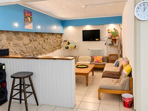 A modern living space with a kitchen area, a sofa set, a wooden table, and a bar stool. - Holiday Home 'Chambre Pour 6 Au Rez De Jardin' with Mountain View, Private Garden and Wi-Fi (Font-Romeu-Odeillo-Via)
