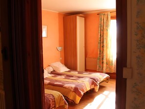 Ein Zimmer mit zwei Betten, einer Stehlampe und einem fenster mit Vorhängen.