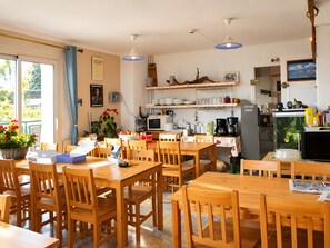 Eine helle, offene Küche und Essbereich mit Holzmöbeln, einem großen Fenster und diversen Küchengeräten.