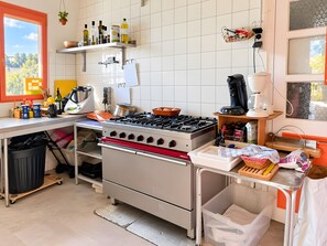 A kitchen with a gas stove, shelves with bottles, a coffee machine, and a trash bin. - Holiday Home 'Chambre Pour 4 Au RDChaussée' with Mountain View, Shared Terrace and Wi-Fi (Font-Romeu-Odeillo-Via)