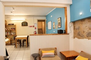 A room with a kitchenette, a dining area with a table and chairs, a bookshelf, and a blue accent wall. - Holiday Home 'Chambre Pour 7 Au RDJardin' with Mountain View, Shared Terrace and Wi-Fi (Font-Romeu-Odeillo-Via)