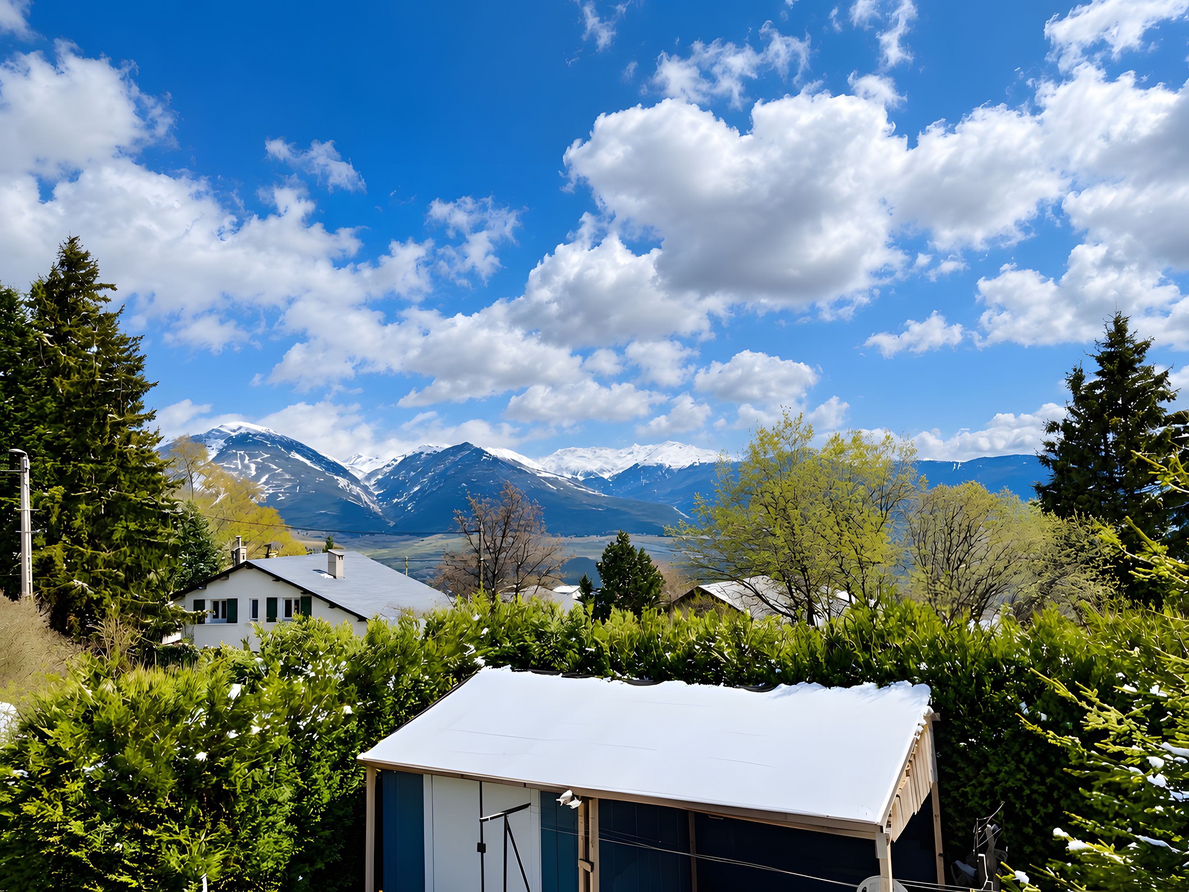 Ein Wohngebiet mit Häusern, blauem Himmel und schneebedeckten Bergen im Hintergrund.
