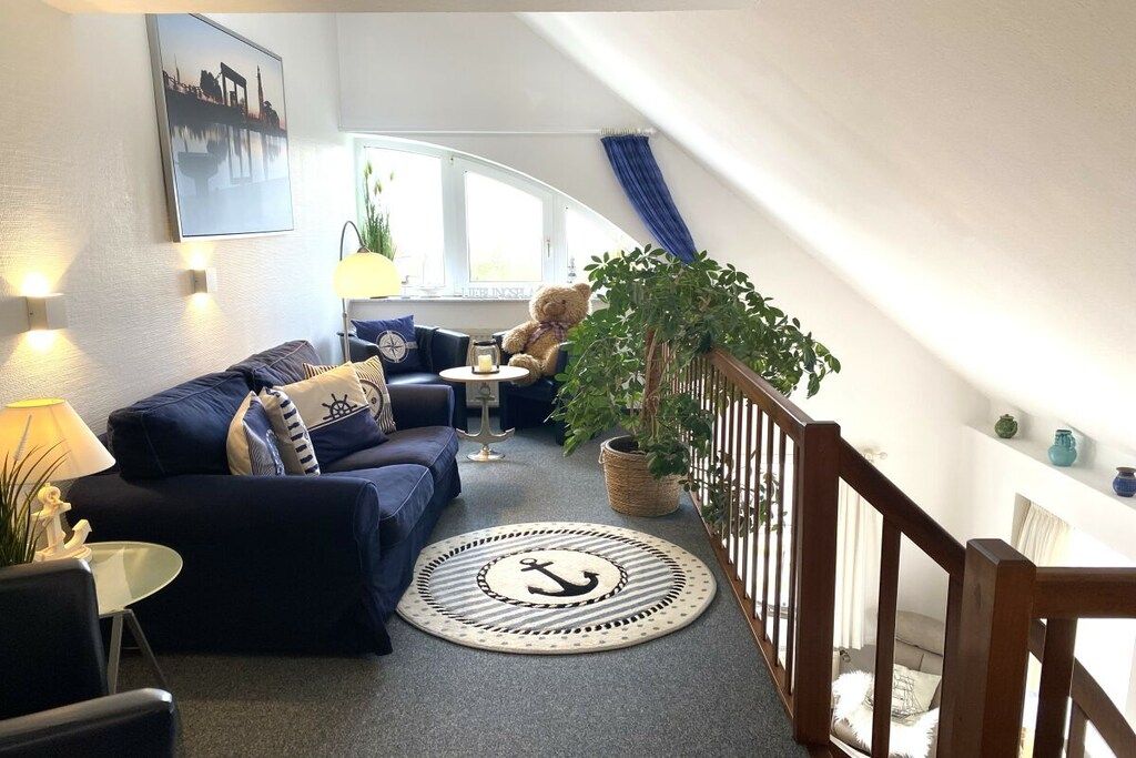 A cozy living room with a sofa, a small table, a lamp, a potted plant, and a view of the outside.
