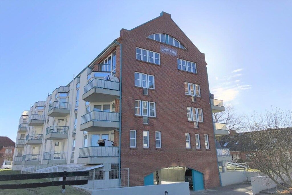 Un edificio a più piani con facciata in mattoni, diversi balconi e un cartello che indica che si tratta di un padiglione.