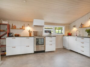 Una cocina moderna con muebles blancos, electrodomésticos de acero inoxidable y detalles de madera.
