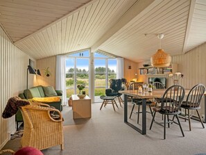 Een gezellig interieur met een eethoek, een bank en een rieten stoel.