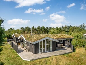 Een modern huis met een groot terras, een overdekte zithoek buiten en een gazon op het dak.