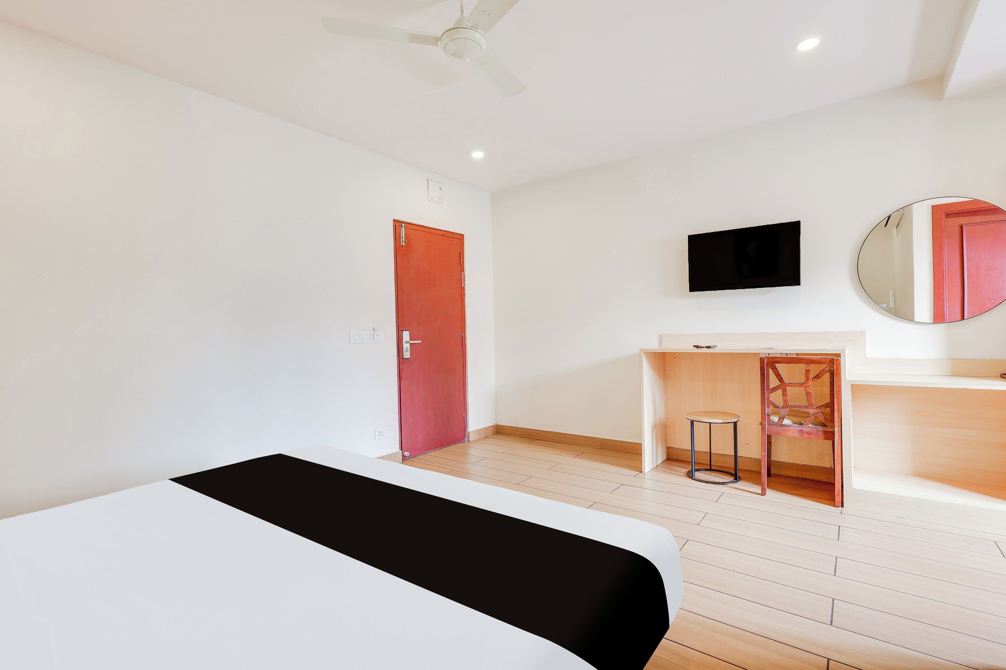 Una habitación de hotel con cama, escritorio, silla, televisor y espejo.