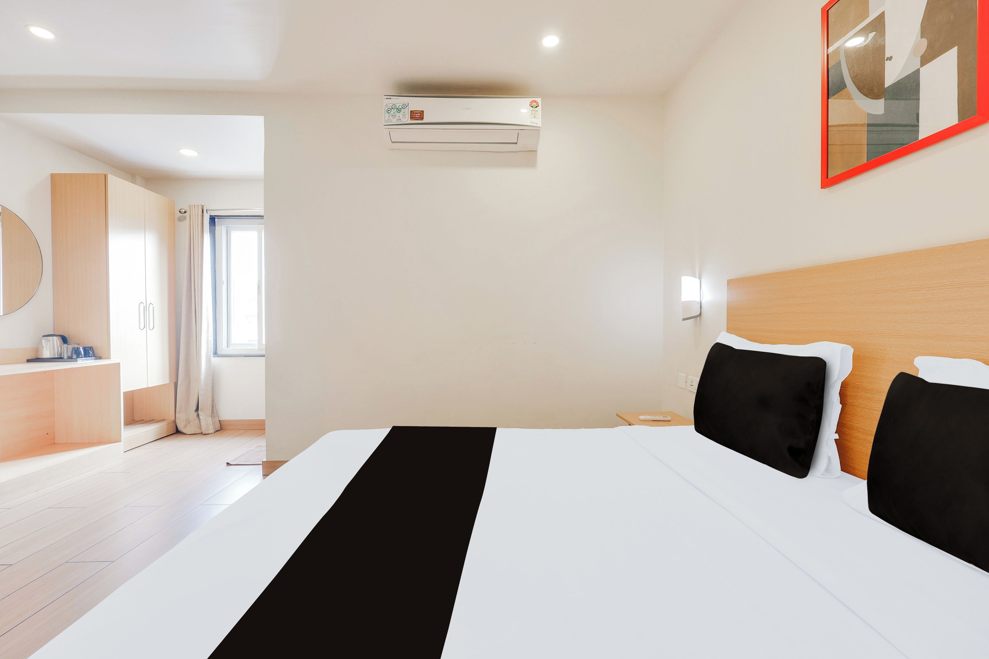 Une chambre d’hôtel comprenant un lit, une table de chevet, un miroir, un appareil de climatisation et donnant sur la salle de bain.