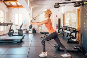Een fitnessruimte met trainingsapparatuur, een loopband en gewichten.
