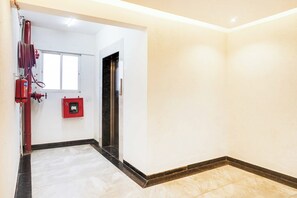 Un pasillo con un extintor, una caja roja de emergencia y una puerta.